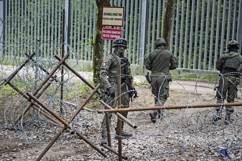 Två soldater som står bakom en barriär av taggtråd.